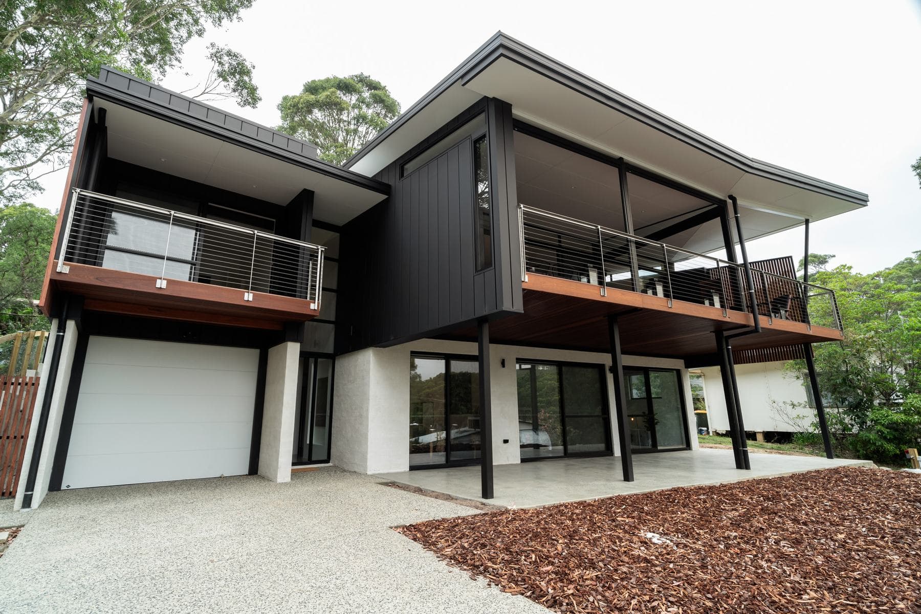 Custom new home by Perrem with dark cladding, timber soffits and a balcony, Batemans Bay