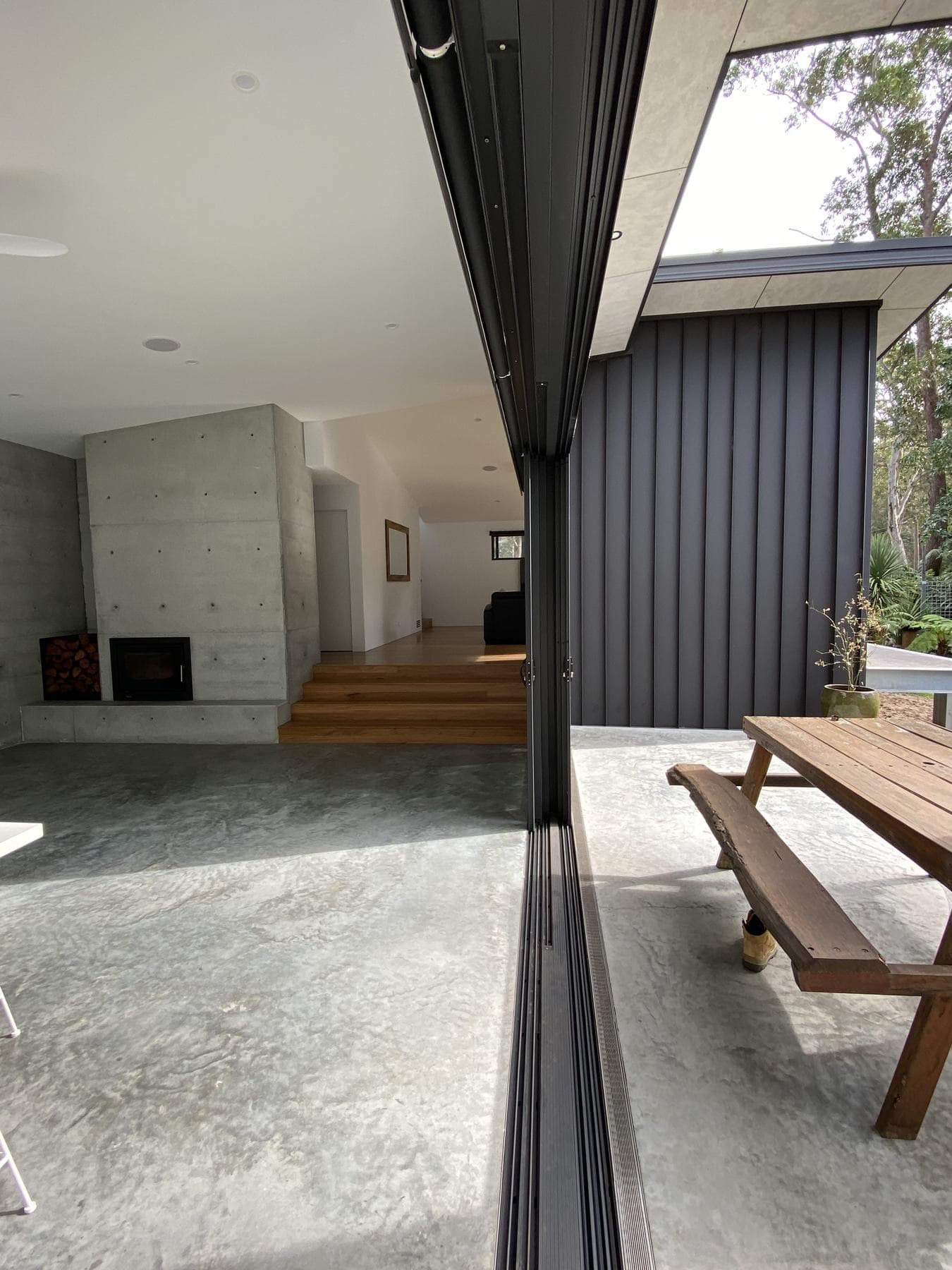 Concrete and dark metal cladding with a timber step down to the living area